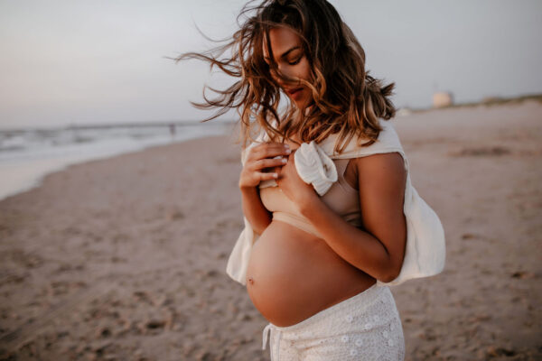 zwangere vrouw buiten bij zee op strand