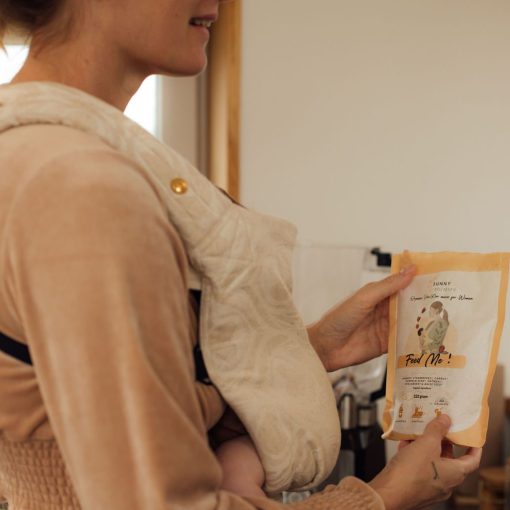 vrouw met baby in draagzak heeft zak superfood in handen