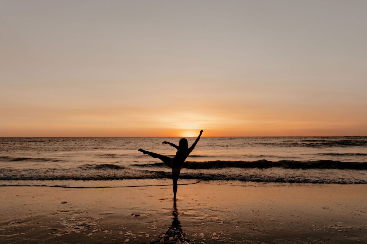 zwangere in balans yoga houding aan zee