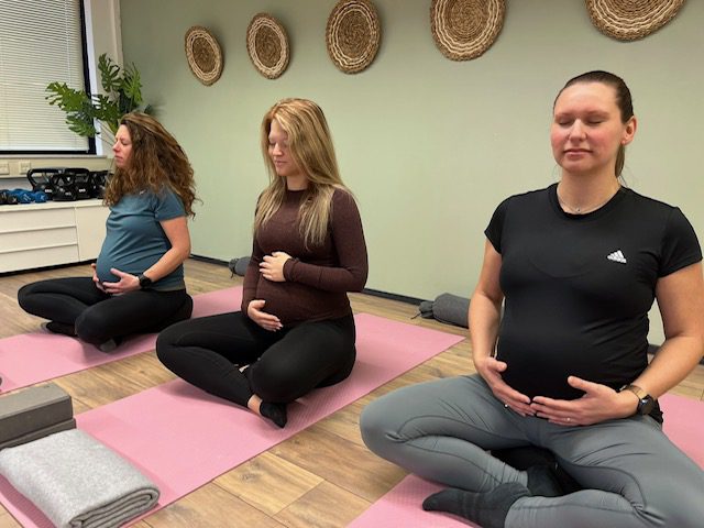groepje zwangere vrouwen oefenen ademhalingstechniek door de buik