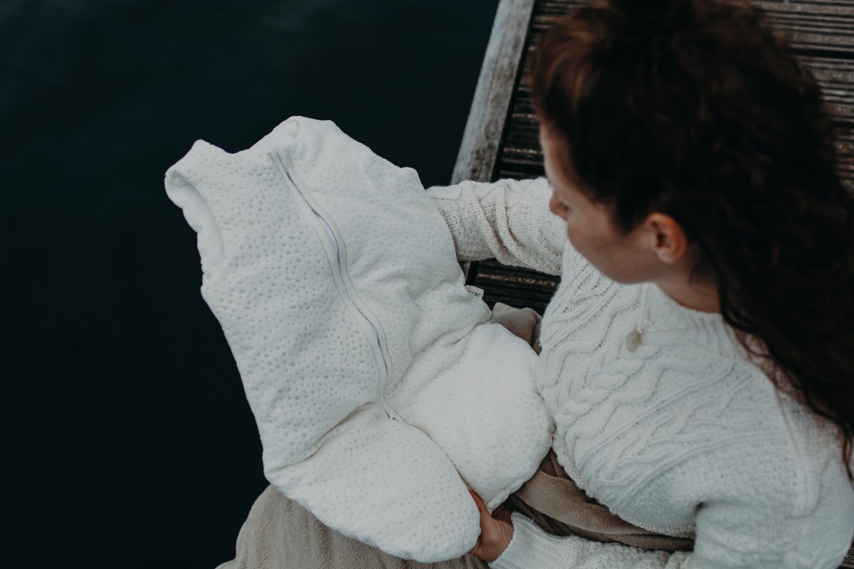 vrouw met babyslaapzak aan water doet wens