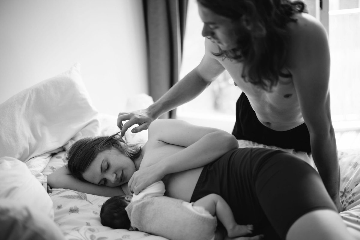 ouders met baby, moeder geeft borstvoeding, vader zorgzaam