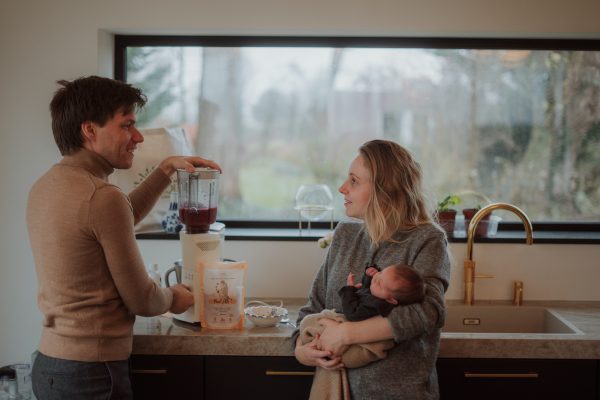 vader en moeder met baby in keuken met smoothie en superfoods