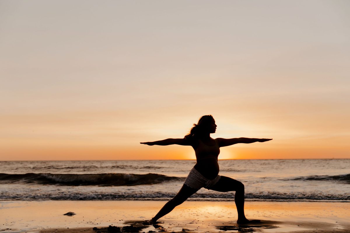 zwangere vrouw bij zonsondergang in yoga houding