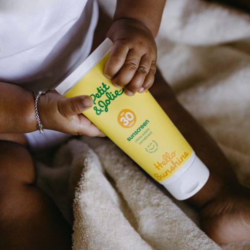 baby houdt tube minerale zonnebrandcreme in handjes