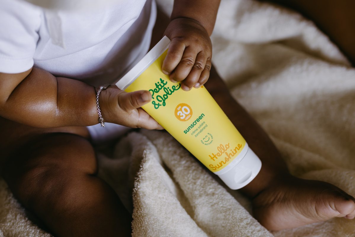 baby houdt tube zonnebrand in zijn handjes