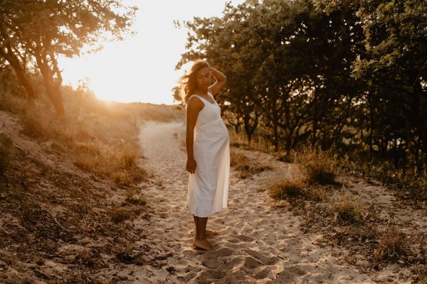 zwangere vrouw bij zonsondergang in de natuur