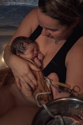 net bevallen vrouw met baby in bad, cordring en placenta zitten er nog aan
