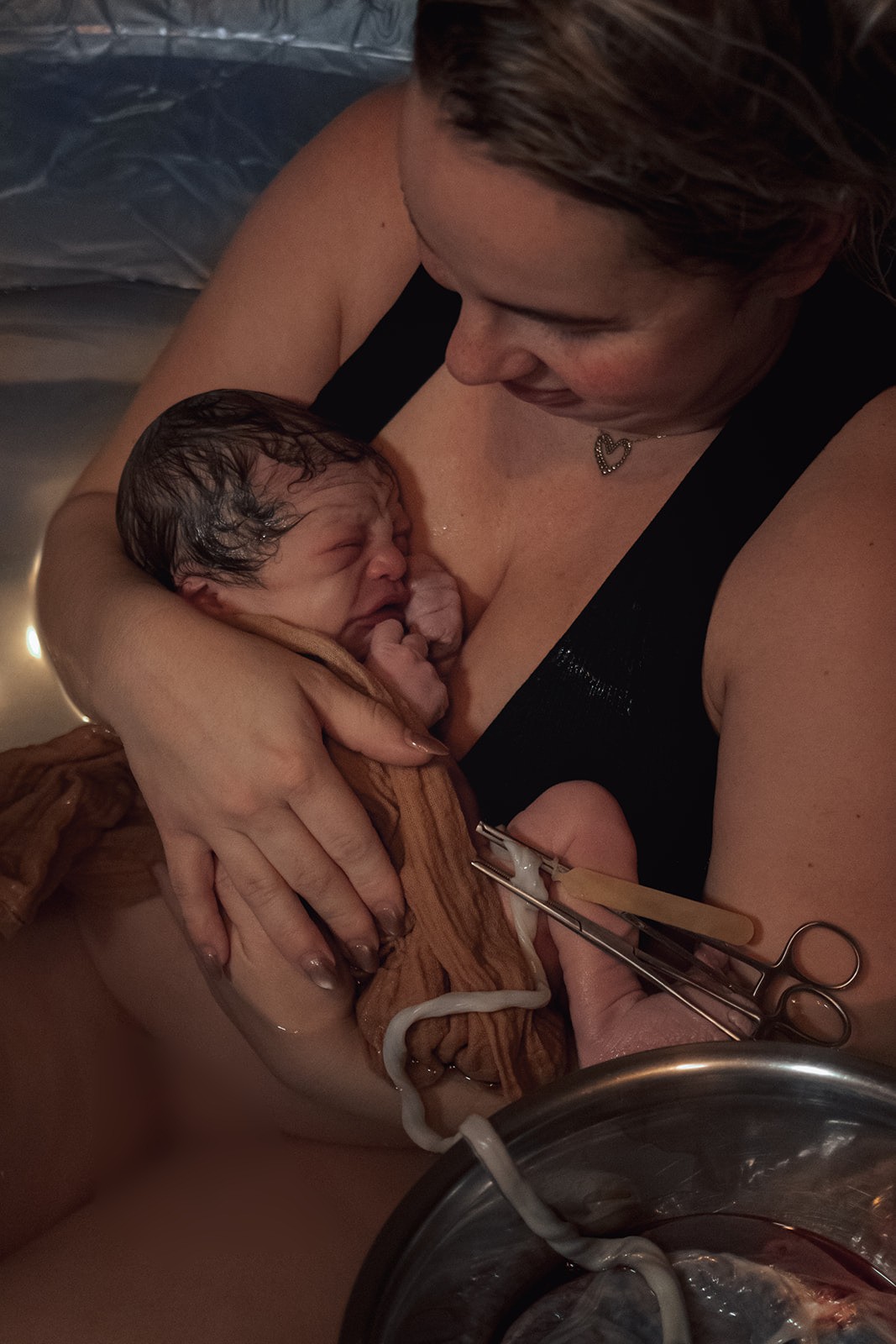 net bevallen vrouw met baby in bad, cordring en placenta zitten er nog aan