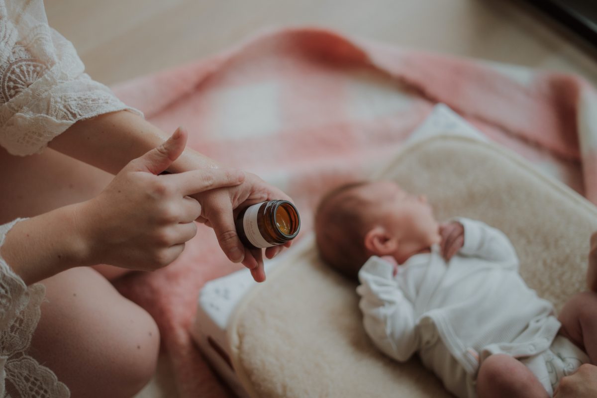baby ligt op verschoningskussen en moeder heeft babyzalf