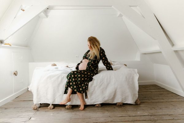 zwangere vrouw op bed met hand op buik