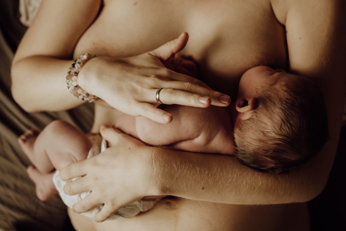 moeder raakt baby aan met handen tijdens borstvoeding