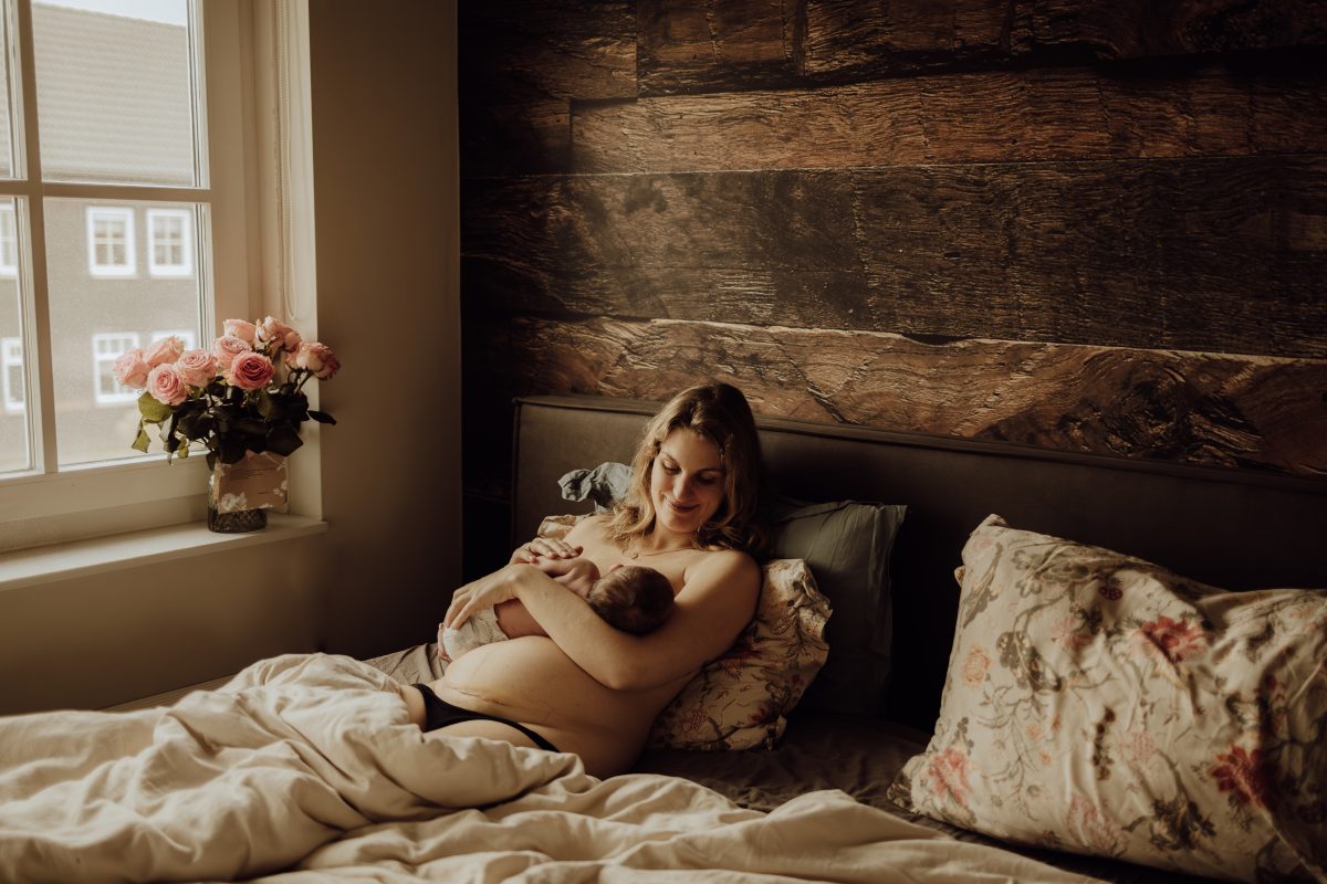 moeder in kraambed met baby aan de borst halfliggende houding